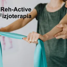 Pacjentka ćwiczy z niebieską gumą pod nadzorem specjalisty w zielonym uniformie, w tle plakat z układem kostnym człowieka.