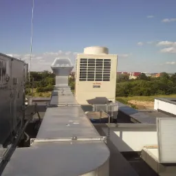 Instalacja wentylacyjna na dachu budynku we Wrocławiu, widoczne kanały wentylacyjne, centrala wentylacyjna marki Toshiba i elementy systemu rekuperacji. W tle zabudowa miejska i błękitne niebo.