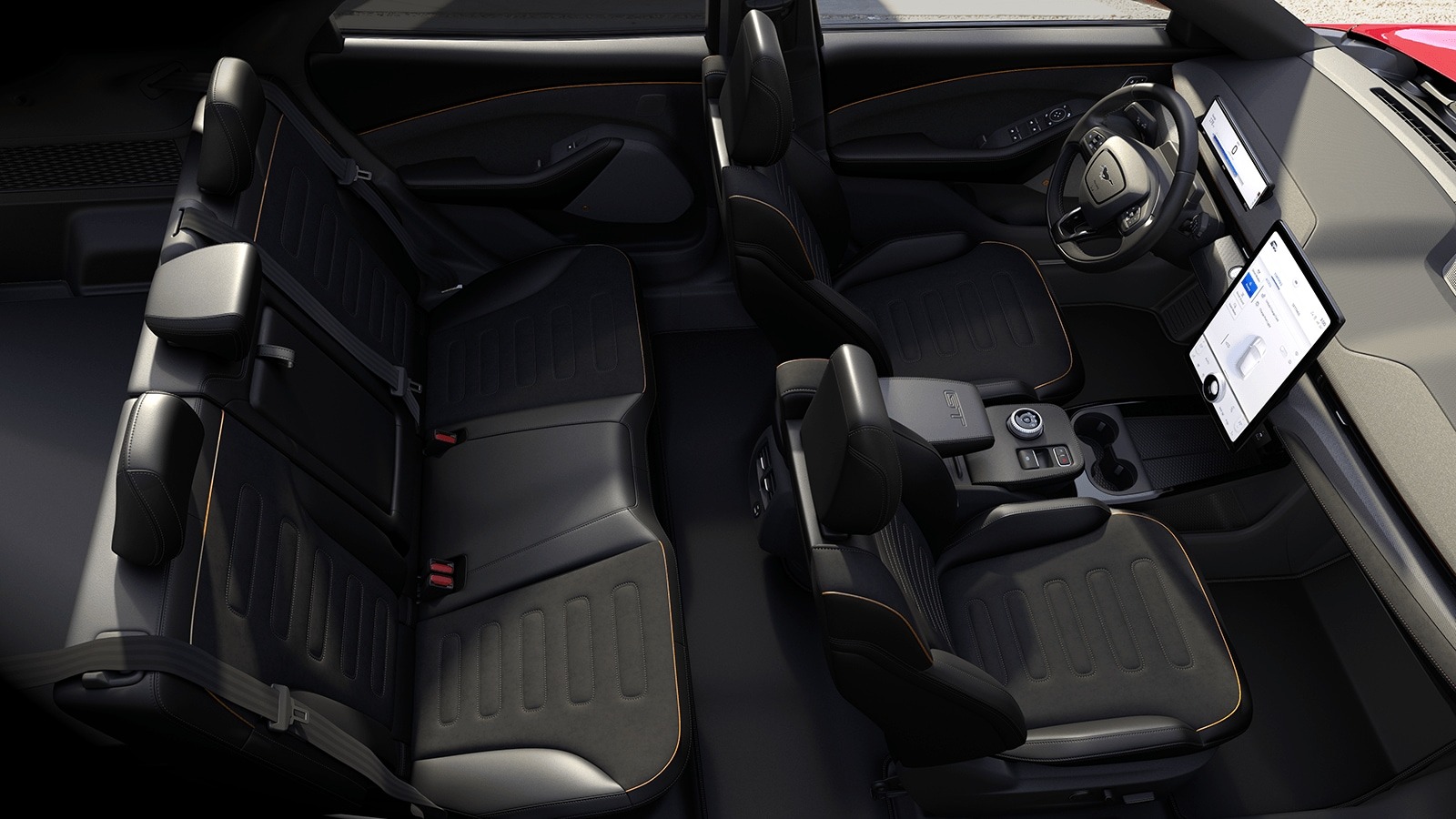Wnętrze samochodu z czarną skórzaną tapicerką, widok z góry na przednie i tylne siedzenia z subtelnymi pomarańczowymi akcentami, duży ekran dotykowy na desce rozdzielczej.