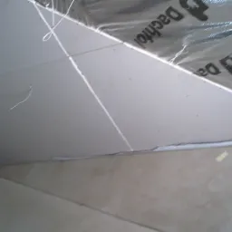 Montaż płyty karton gips na suficie, widoczne profile i folia paroizolacyjna Dachfol, częściowo zamontowane płyty, surowy stan wykończenia.