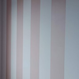 Jeszcze nie ma działalności - Pomalowana ściana w pionowe pasy w odcieniach pudrowego różu i bieli, widok z dołu ukazujący wzór na ścianie, świeżo po malowaniu.