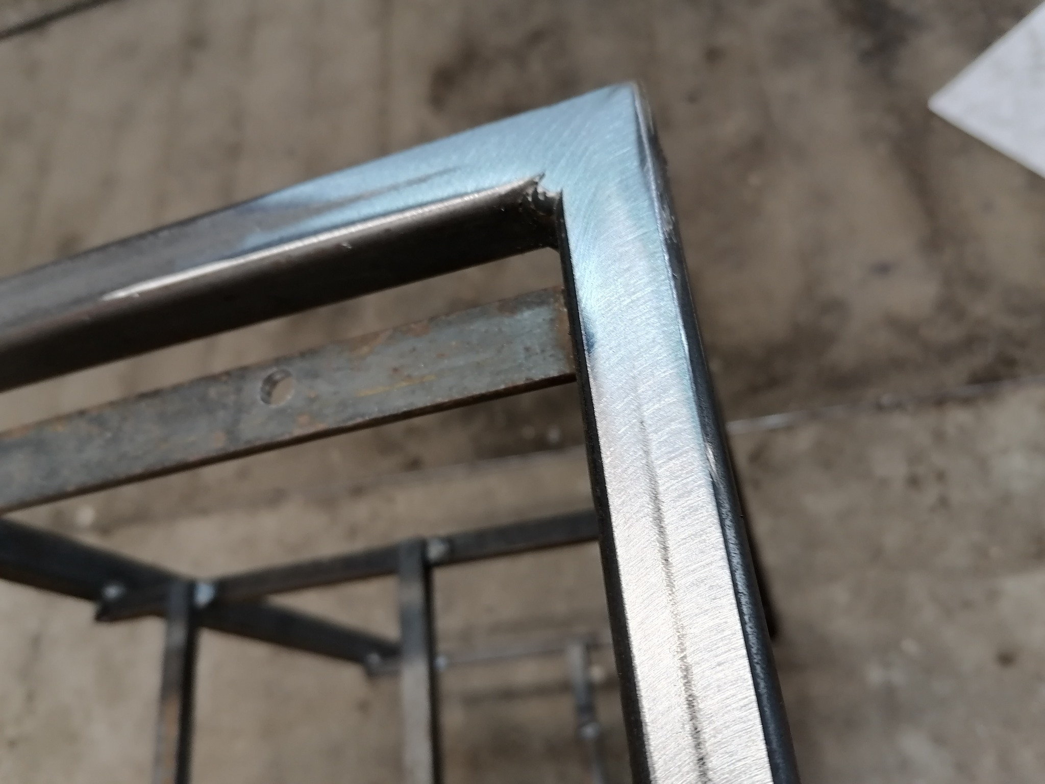 Spawana konstrukcja metalowa z profili o przekroju kwadratowym, widoczne spawy i szlifowane powierzchnie w surowym stanie.