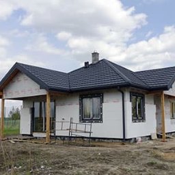 AK.MK Bud - Dom jednorodzinny w trakcie ocieplania elewacji, widoczne płyty styropianowe i rusztowanie pomocnicze.