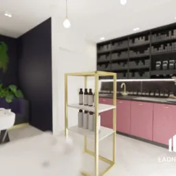Wnętrze salonu fryzjerskiego z wyposażeniem: stanowisko do mycia włosów, regał na produkty i szafki w kolorze pudrowego różu z czarnym blatem, oświetlone lampami sufitowymi i neonem roślinnym.