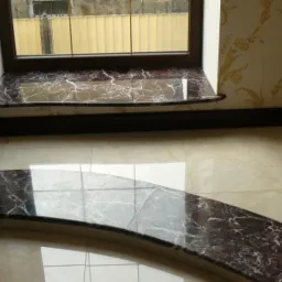 Wnętrze z marmurowym parapetem okiennym i wykończeniem schodów z tego samego materiału, dopasowane do koloru podłogi z płytek.