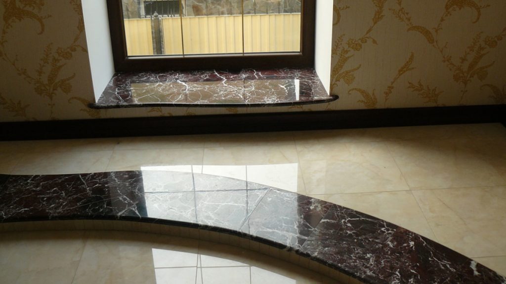 Wnętrze z marmurowym parapetem okiennym i wykończeniem schodów z tego samego materiału, dopasowane do koloru podłogi z płytek.