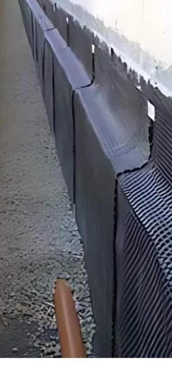 Hydroizolacja fundamentów z użyciem folii kubełkowej, widoczne połączenia i fragment dłoni wskazujący na szczegół konstrukcyjny.