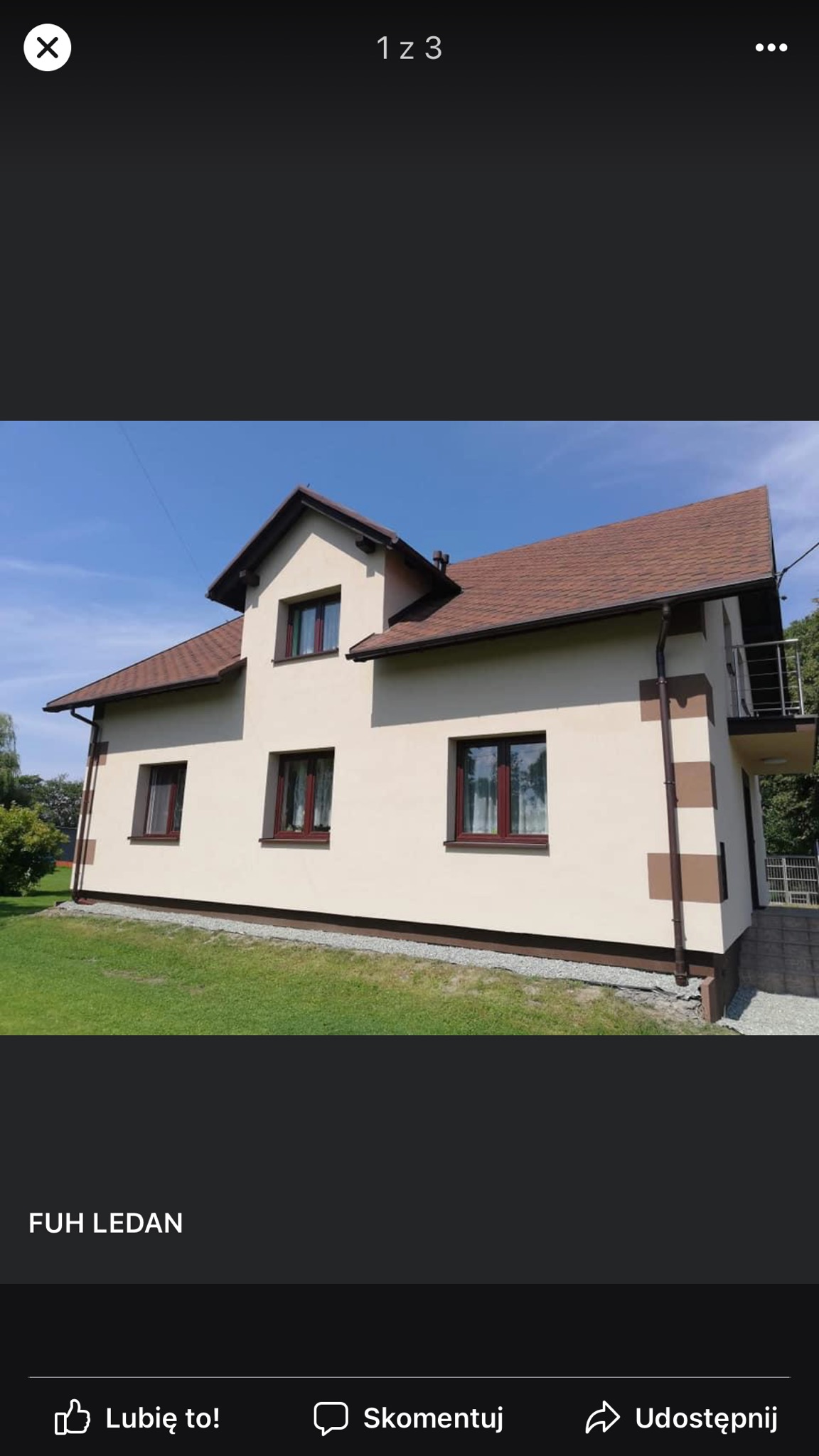 Otynkowany i pomalowany dom jednorodzinny z brązowymi oknami i dachem z gontu bitumicznego, widoczny fragment balkonu z metalową barierką.