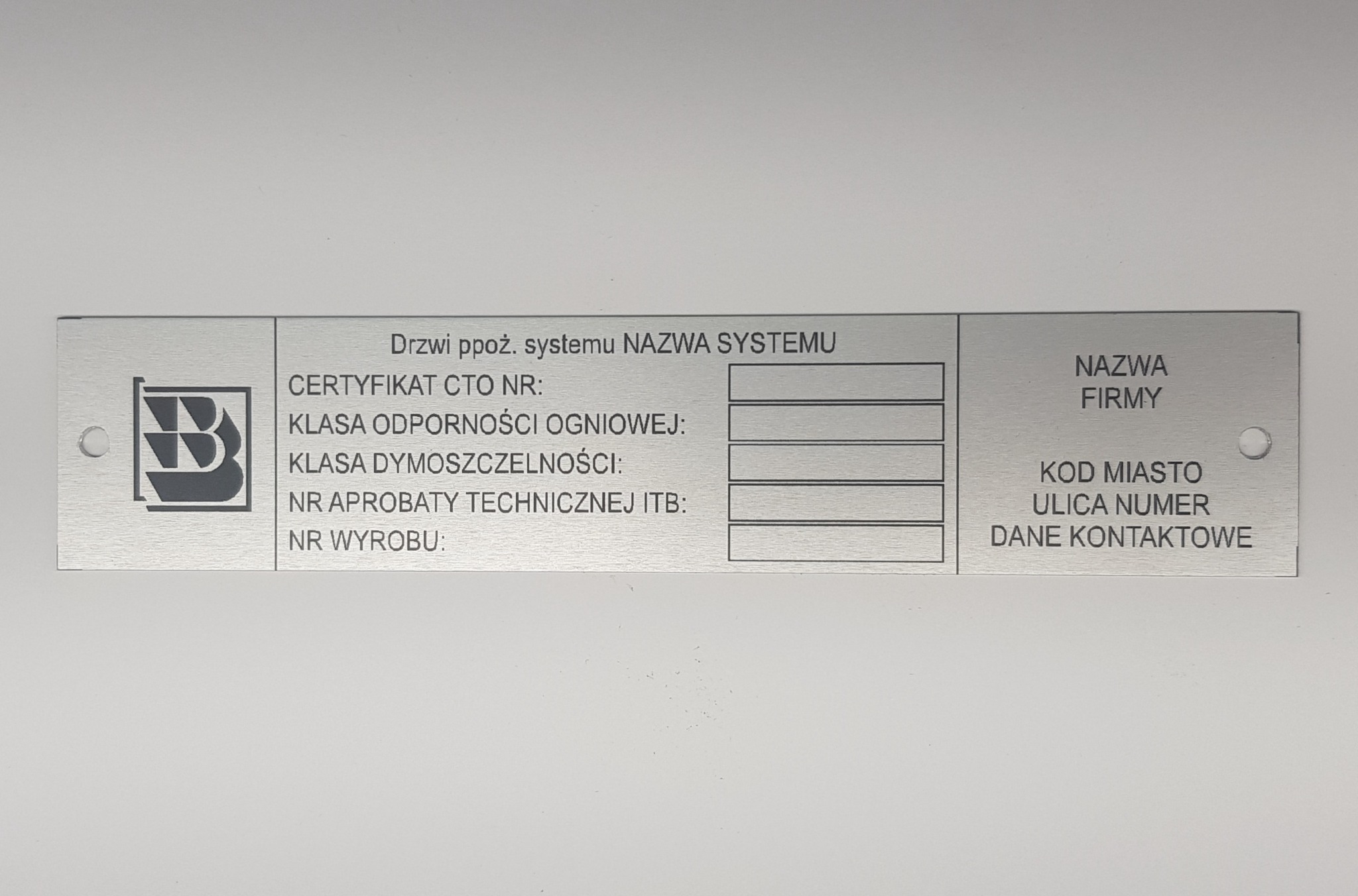 Metalowa tabliczka znamionowa drzwi przeciwpożarowych z logo, polami na certyfikat CTO, klasę odporności ogniowej, klasę dymoszczelności, numer aprobaty technicznej ITB, numer wyrobu oraz danymi...