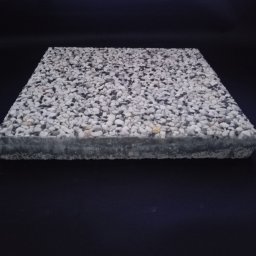 Z.P.B. “Taras” Rozpendkowski Marian - Kwadratowa płyta chodnikowa z białych i szarych kamyczków na ciemnym tle, widok z boku.