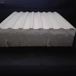 Betonowa płyta chodnikowa z rowkami na czarnym tle, widok z przodu, ukazujący strukturę betonu.