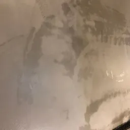 Świeżo umyta, mokra podłoga betonowa z widocznymi śladami opon i odpływem liniowym w prawym dolnym rogu.