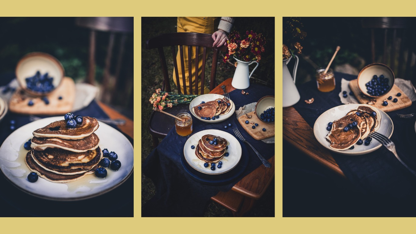 Stylizowana kompozycja z naleśnikami i borówkami na stole w plenerze, z elementami rustykalnymi i naturalnym oświetleniem, tworząca apetyczną scenę.