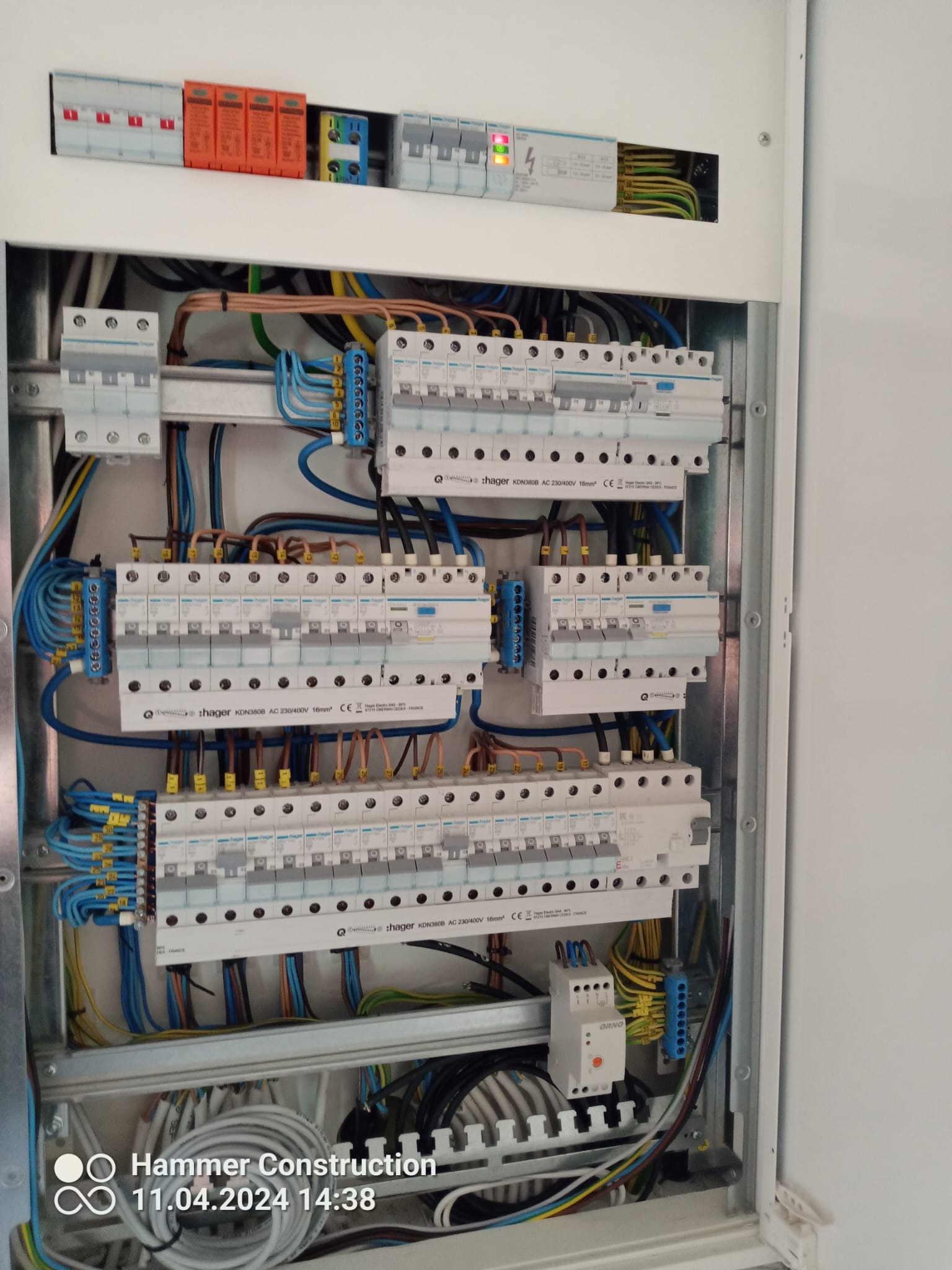 Rozdzielnica elektryczna z zainstalowanymi bezpiecznikami, przewodami i listwami zaciskowymi, widok z bliska na uporządkowane okablowanie wewnątrz białej skrzynki.