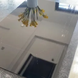 Błyszcząca, czarna płyta indukcyjna Electrolux z odbiciem bukietu żółtych kwiatów w wazonie, stojąca na blacie z szarego lastryko.