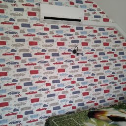 NOVO-TECH Sławomir Czmiel - Biały klimatyzator LG zamontowany na ścianie z tapetą w kolorowe samochody i motocykle w pokoju na poddaszu.