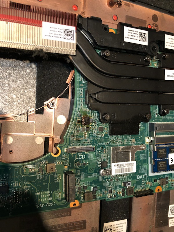 Wnętrze otwartego laptopa z widoczną płytą główną, elementami chłodzenia i baterią, z bliska, ukazujące detale elektroniki i potencjalne uszkodzenia.