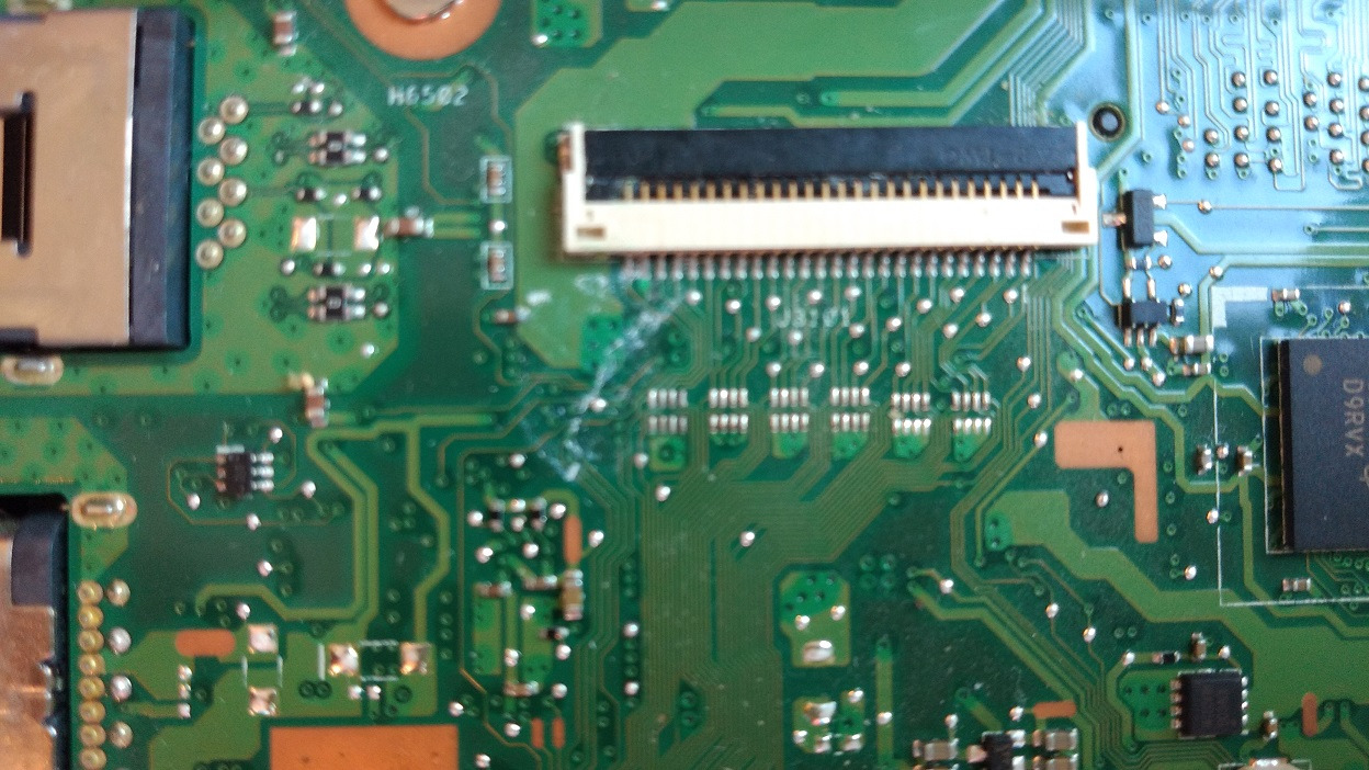 Zbliżenie na zieloną płytę główną laptopa z widocznymi elementami elektronicznymi, złączami i śladami po cieczy.