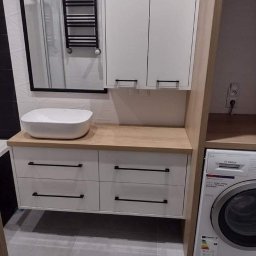 P. H. U. Dan-Bud Daniel Miszczak - Nowoczesna łazienka z białymi szafkami z czarnymi uchwytami, drewnianym blatem i umywalką nablatową, obok pralka Bosch