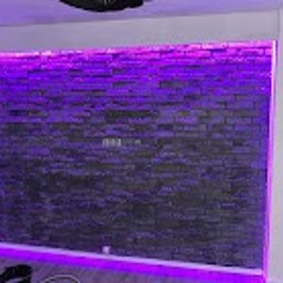 AKR Remonty - Ściana z dekoracyjnej cegły, podświetlona fioletowym światłem LED, tworząca nowoczesny efekt wizualny we wnętrzu.