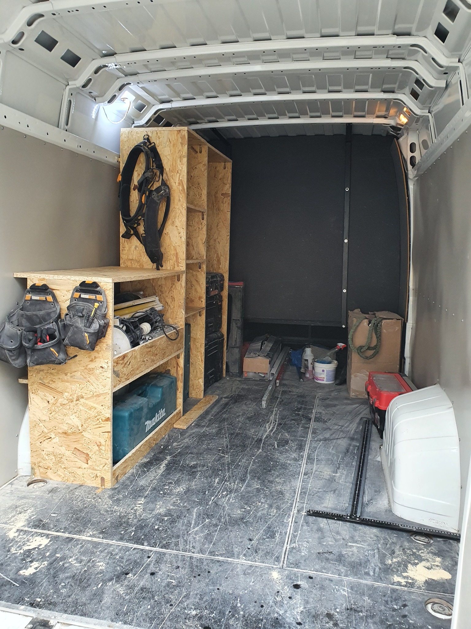 Wnętrze furgonetki z zabudową warsztatową z płyty OSB, widoczne narzędzia, skrzynki i pas monterski, Bydgoszcz.