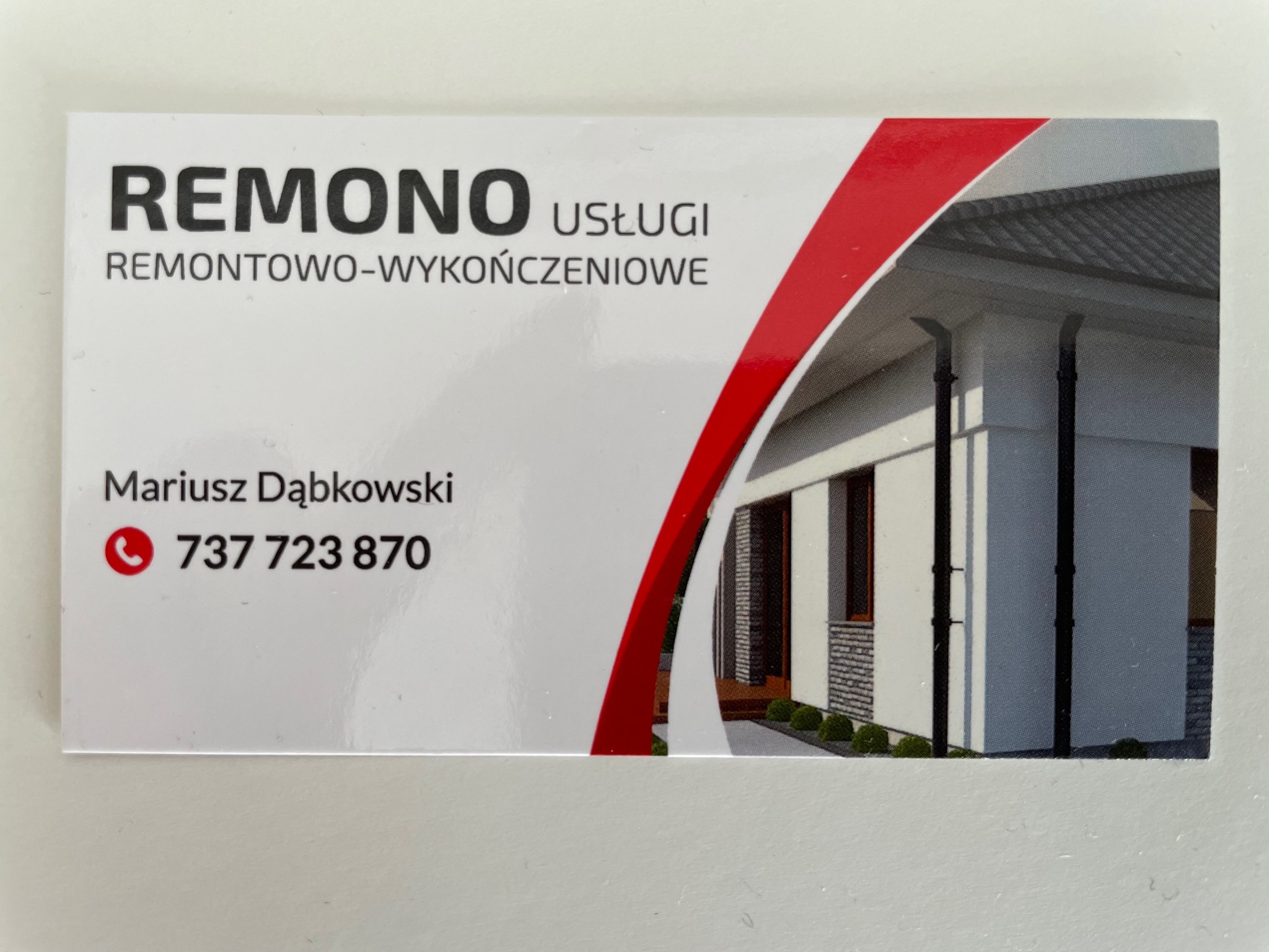 Wizytówka firmy REMONO Usługi remontowo-wykończeniowe z numerem telefonu Mariusza Dąbkowskiego, z graficznym przedstawieniem elewacji budynku z oknami i dachem.