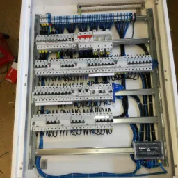 Rozdzielnica elektryczna z zainstalowanymi bezpiecznikami i okablowaniem w estetycznej białej obudowie, widok z góry, instalacja wykonana w Radzyminie.