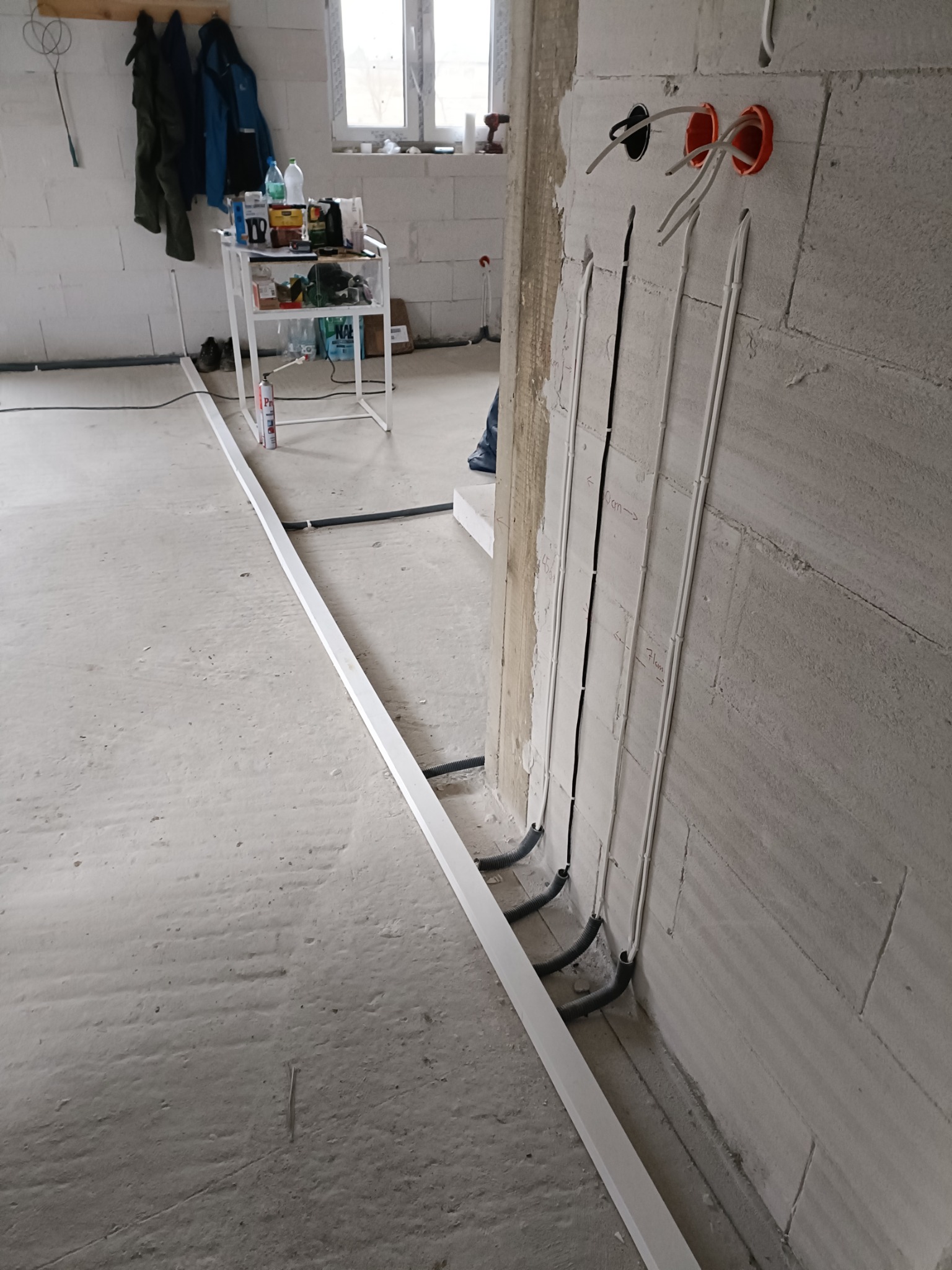 Świeżo położone przewody elektryczne w peszlach, prowadzone w bruzdach w ścianie z betonu komórkowego w Kielcach, przygotowane do dalszych prac wykończeniowych.