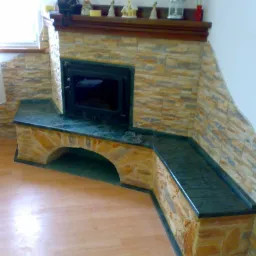 Obudowa kominka z kamienia naturalnego i blatem z ciemnego kamienia, wykończona dekoracyjną półką i drobnymi ozdobami.