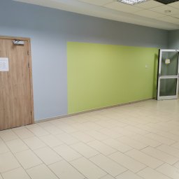 TP REMONTY I WYKOŃCZENIA - Pomalowane ściany w biurze na szaro i jasnozielono, z dwiema drewnianymi futrynami drzwi i białą futryną, kremowa podłoga z płytek.