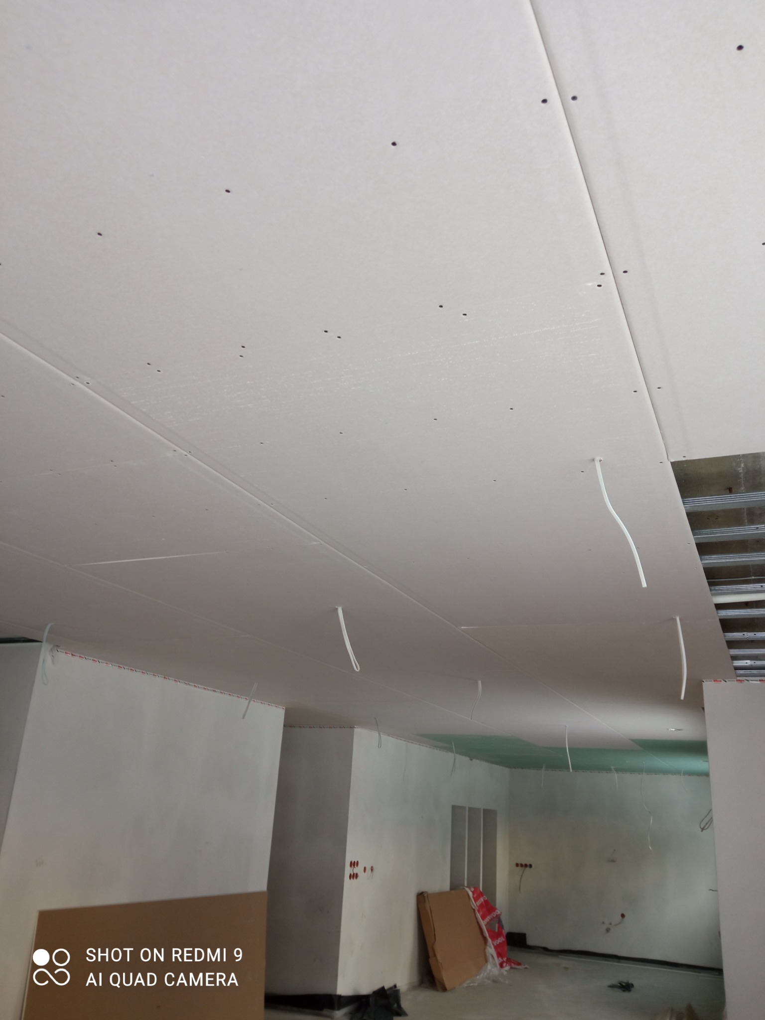 Sufit z zamontowaną płytą kartonowo-gipsową w trakcie prac wykończeniowych w Rzeszowie. Widoczne kable wystające z sufitu, konstrukcja metalowa oraz niedokończone ściany.