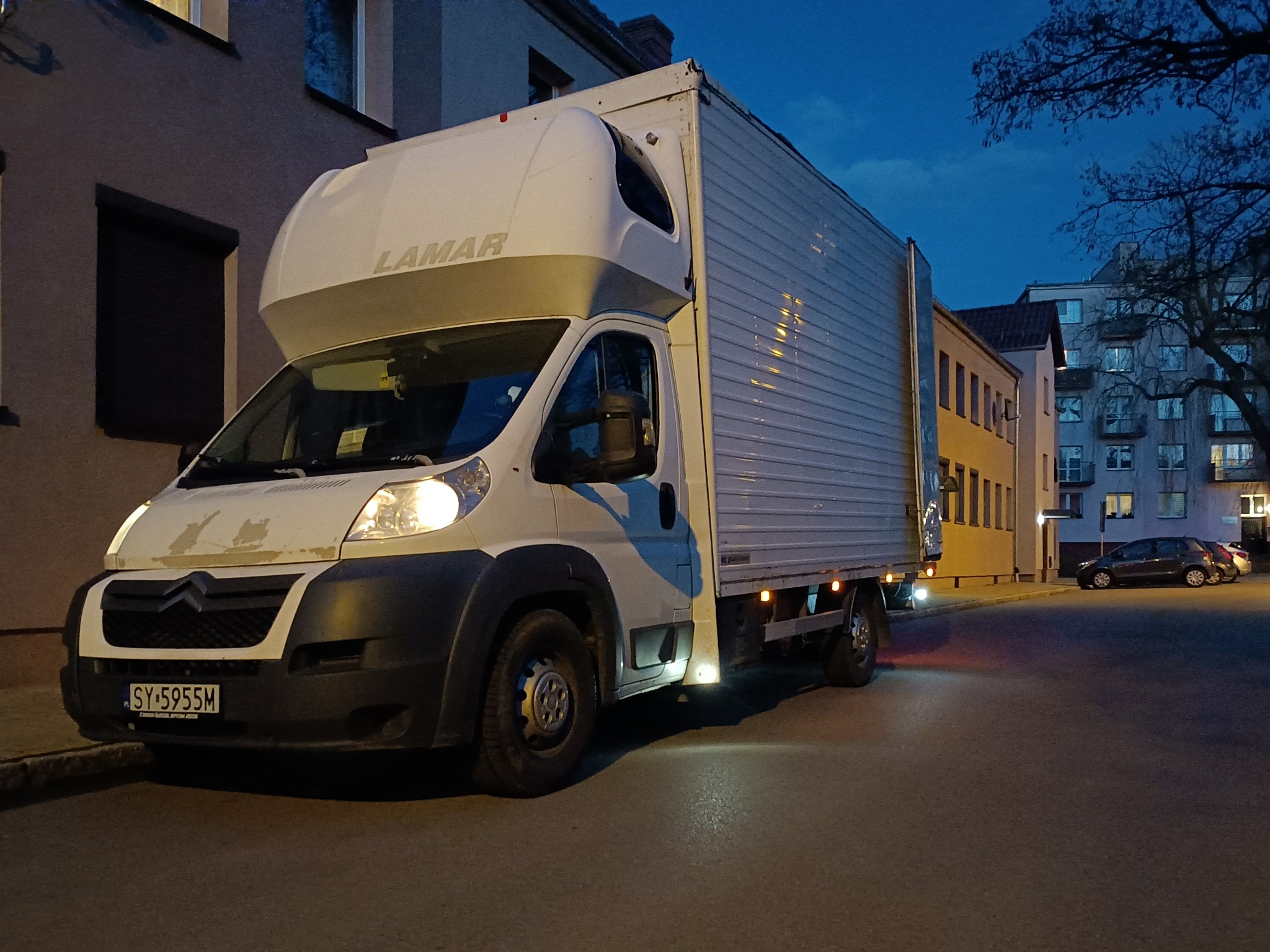Biały samochód dostawczy marki Citroen z zabudową LAMAR zaparkowany na ulicy w scenerii zmierzchu, widoczny numer rejestracyjny SY-5955M.