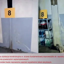 Nieszczelna dylatacja w ścianie fundamentowej z widocznymi śladami wycieku wody, naprawiona poprzez wypełnienie żelem akrylowym, oznaczona żółtą tabliczką z numerem 8.