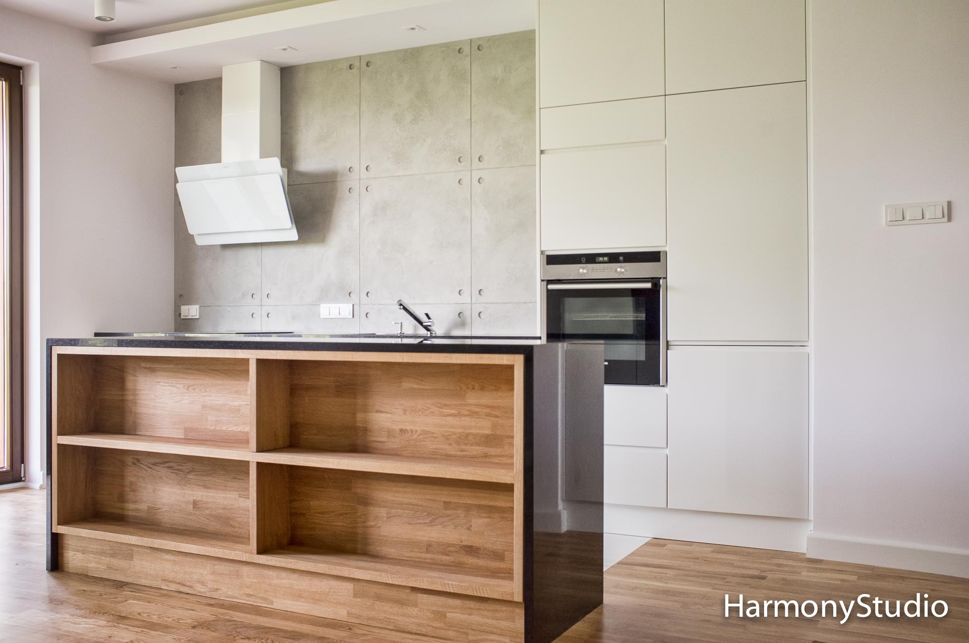 Kuchnia z wyspą otwarta na salon. W zabudowie kuchni białe lakierowane fronty z podchwytem i blat z konglomeratu.