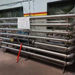 Konstrukcja z rur ze stali nierdzewnej, prawdopodobnie wymiennik ciepła, z poziomnicą w tle, wykonana w Płocku.