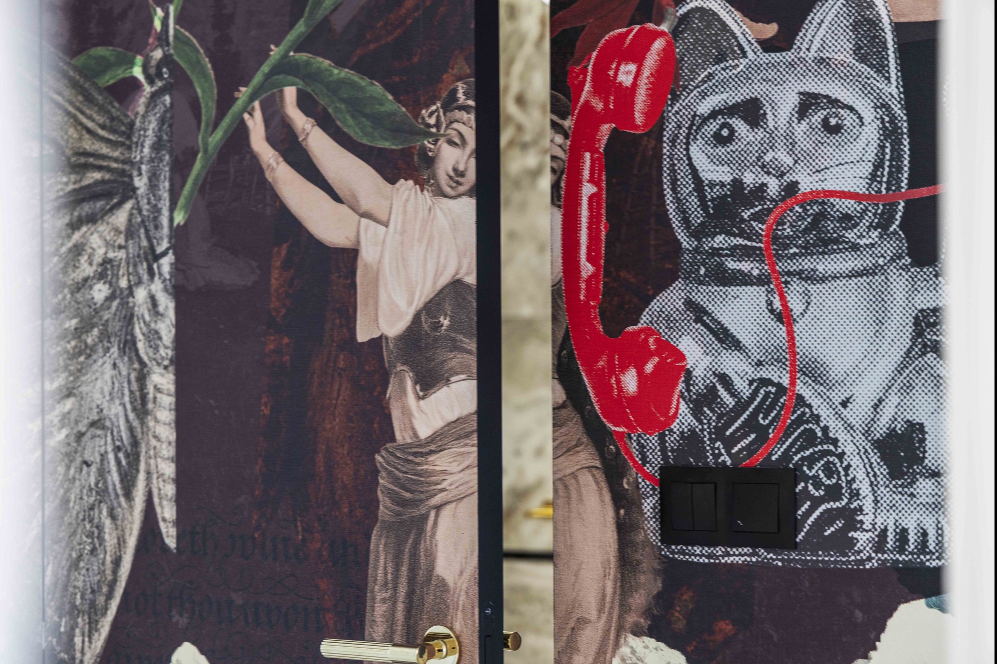 Dwa skrzydła drzwi z unikalnymi wzorami: kobieta z liśćmi i kot w skafandrze z czerwonym telefonem. Złota klamka i czarny włącznik światła dodają charakteru.