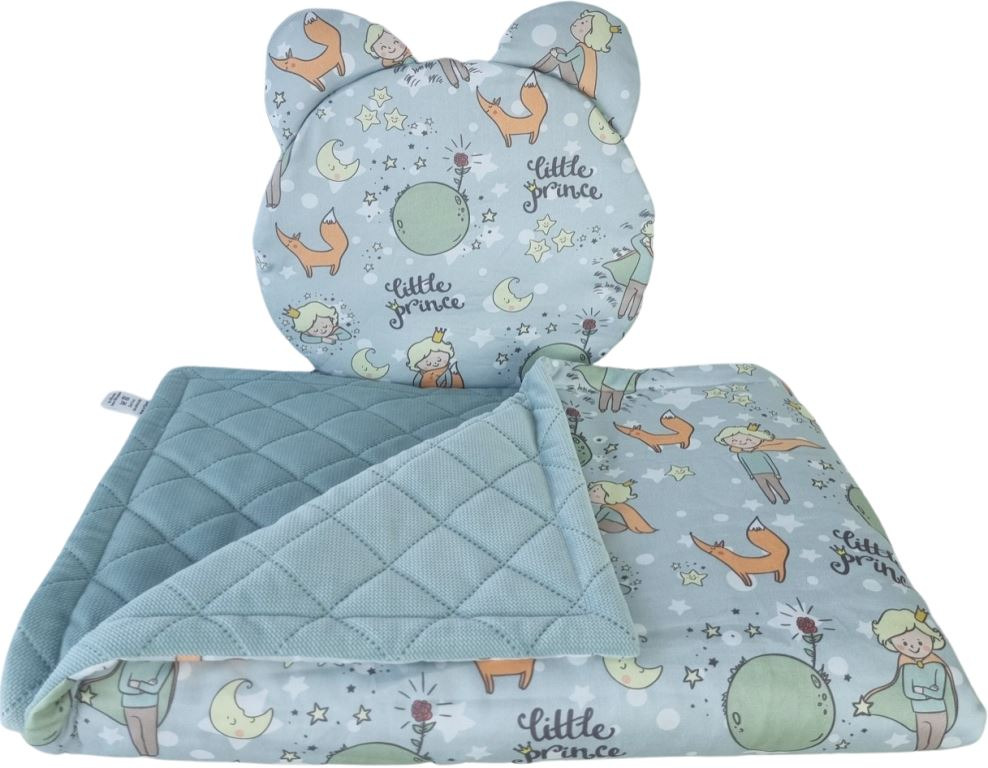 Komplet pościeli dziecięcej: poduszka w kształcie głowy misia i pikowana kołderka z motywem Małego Księcia, utrzymane w pastelowej kolorystyce.