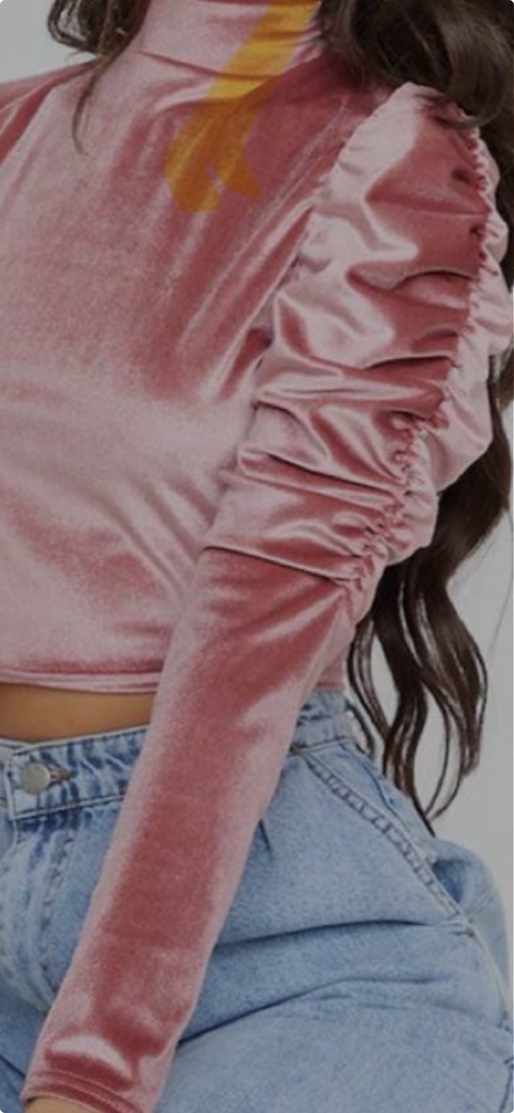 Detale różowej, welurowej bluzki z bufkami na ramionach i długim rękawem, zestawionej z dżinsami.