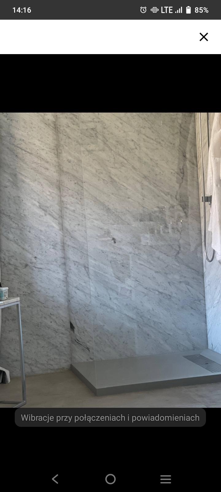 Nowoczesna kabina prysznicowa z marmurowymi ścianami i szklaną przegrodą. Minimalistyczny design z odpływem liniowym w posadzce.