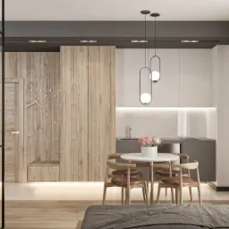 Nowoczesne wnętrze mieszkania z drewnianą zabudową, obejmującą szafę z wnęką i wieszakiem, oraz szarą zabudowę kuchenną z okrągłym stołem i krzesłami w stylu skandynawskim.