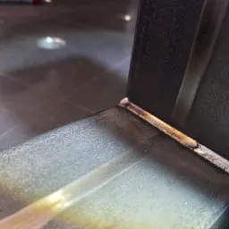 Spoina narożna na metalowym profilu, widoczne przebarwienia termiczne i faktura spoiny.