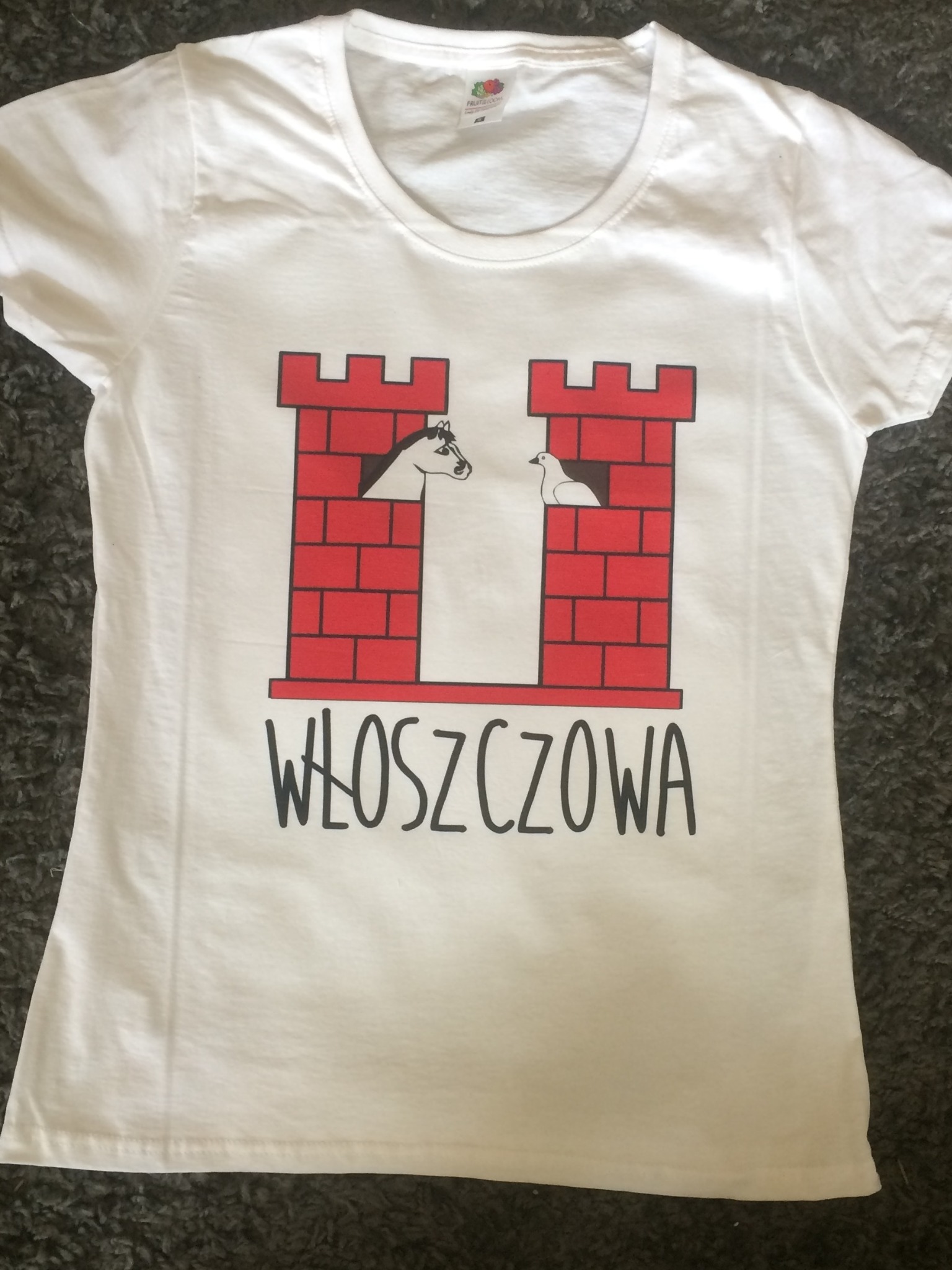 Biała koszulka z nadrukiem przedstawiającym dwie czerwone wieże zamkowe, w jednej koń, w drugiej gołąb oraz napis 'Włoszczowa'.