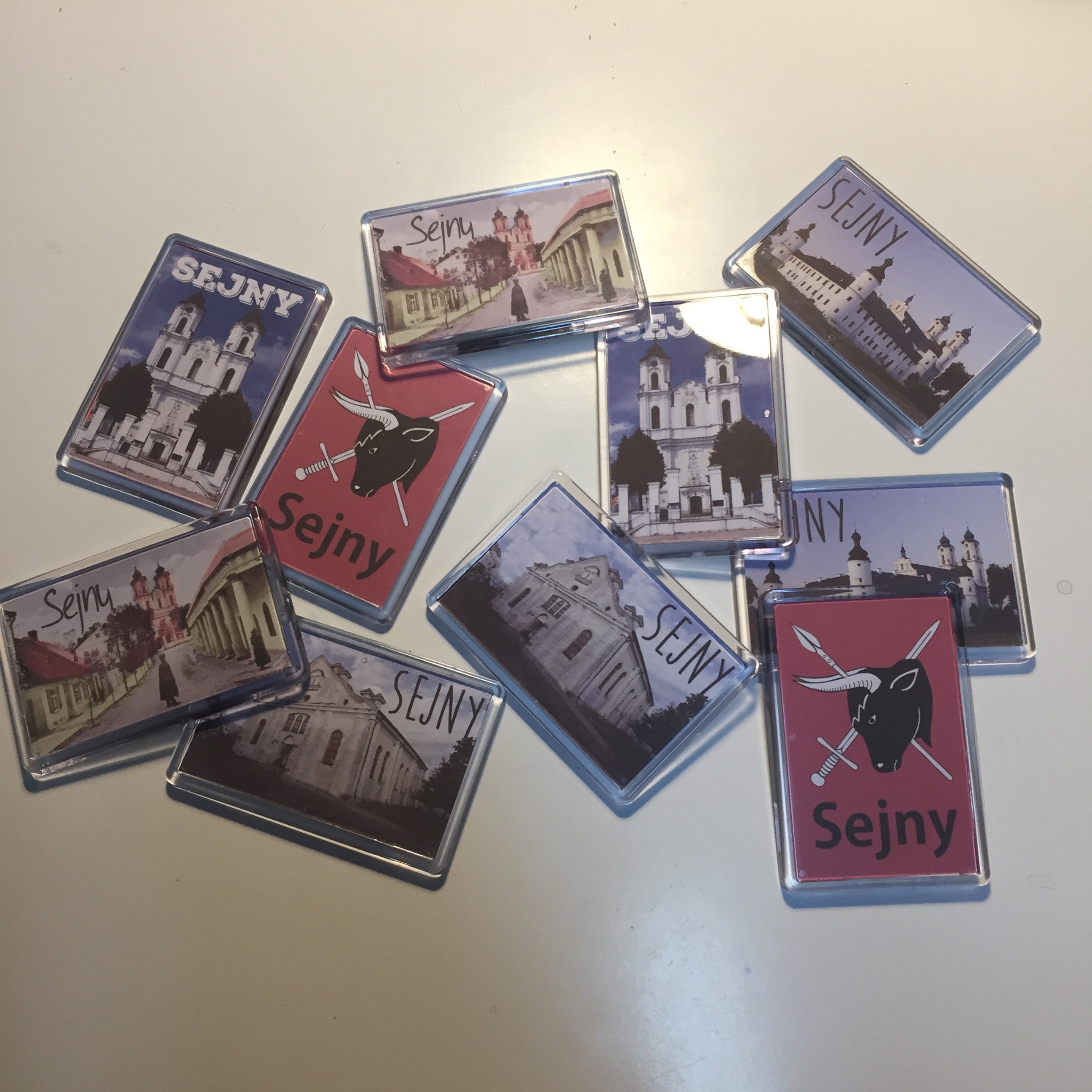 Kolekcja prostokątnych magnesów z widokami i herbem Sejn leżących na białym tle