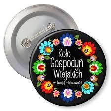 Dwa okrągłe znaczki/przypinki. Jeden z metalowym tyłem i agrafką, drugi z czarnym tłem i kolorowym folkowym wzorem kwiatowym otaczającym napis 'Koło Gospodyń Wiejskich w Twojej miejscowości'.