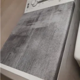 Biała pralka z naklejoną szarą folią imitującą beton na górnej powierzchni.