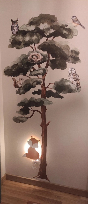 Malowidło ścienne w pokoju dziecięcym: drzewo z sowami, wiewiórką, ptakiem i podświetlanym lisem u podstawy pnia.