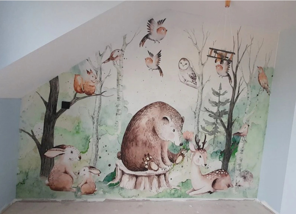Malowidło ścienne w pokoju dziecięcym przedstawiające leśne zwierzęta w stylu akwareli: niedźwiedź na pniu, zające, sowa, jeleń, jeż i ptaki wśród drzew.