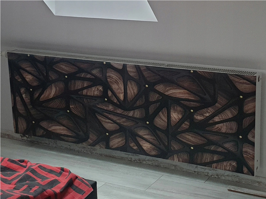 Grzejnik z dekoracyjną obudową w abstrakcyjny wzór drewna i czarnych linii, wykończony złotymi punktami.