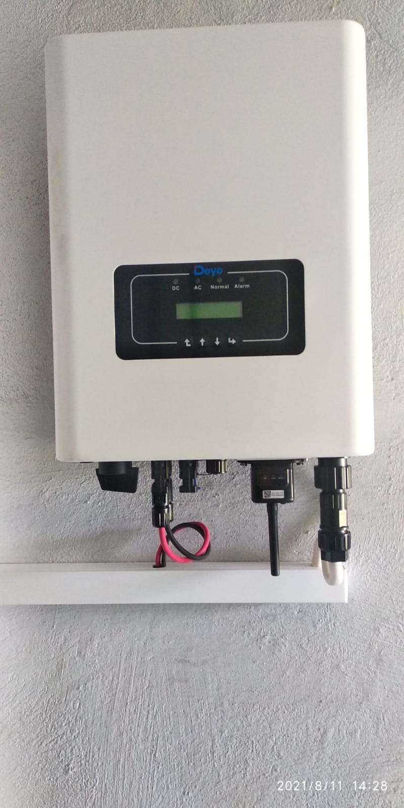 Biały falownik Deye zamontowany na ścianie, widoczne przewody i wyświetlacz z informacjami o stanie pracy.