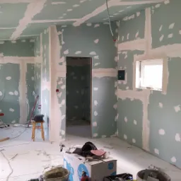 Wnętrze w trakcie montażu płyt kartonowo-gipsowych, widoczne szpachlowane łączenia i narzędzia pracy, surowe wykończenie, kable wystające z sufitu.